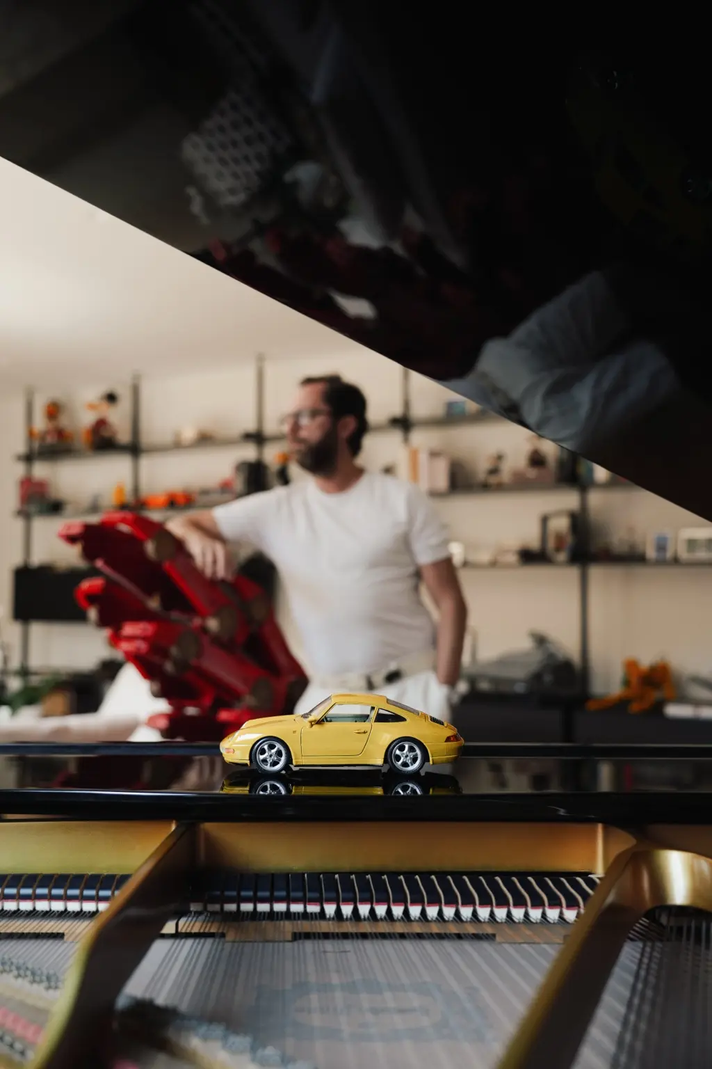 The yellow Porsche 993 model reflected on a grand piano