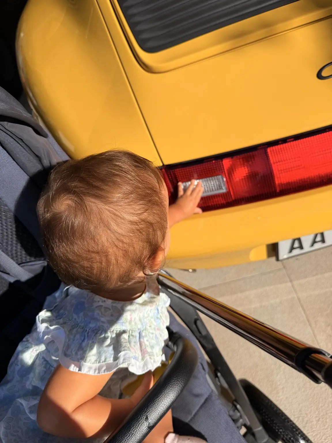 Margherita reaching towards the rear light of the yellow Porsche 993 Daisy