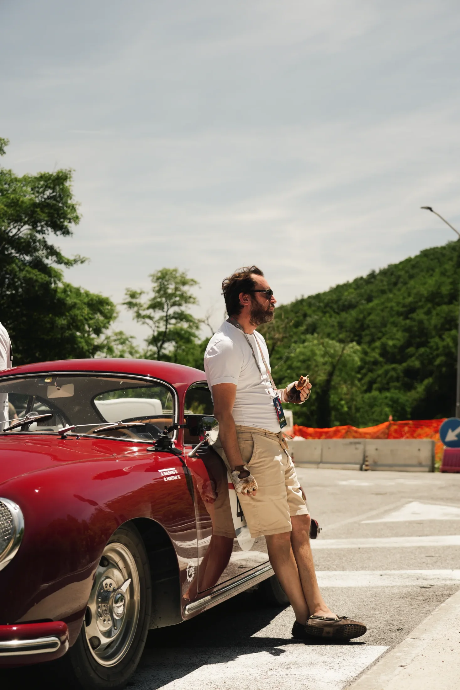 A driver leaning on the Porsche during a road stop.