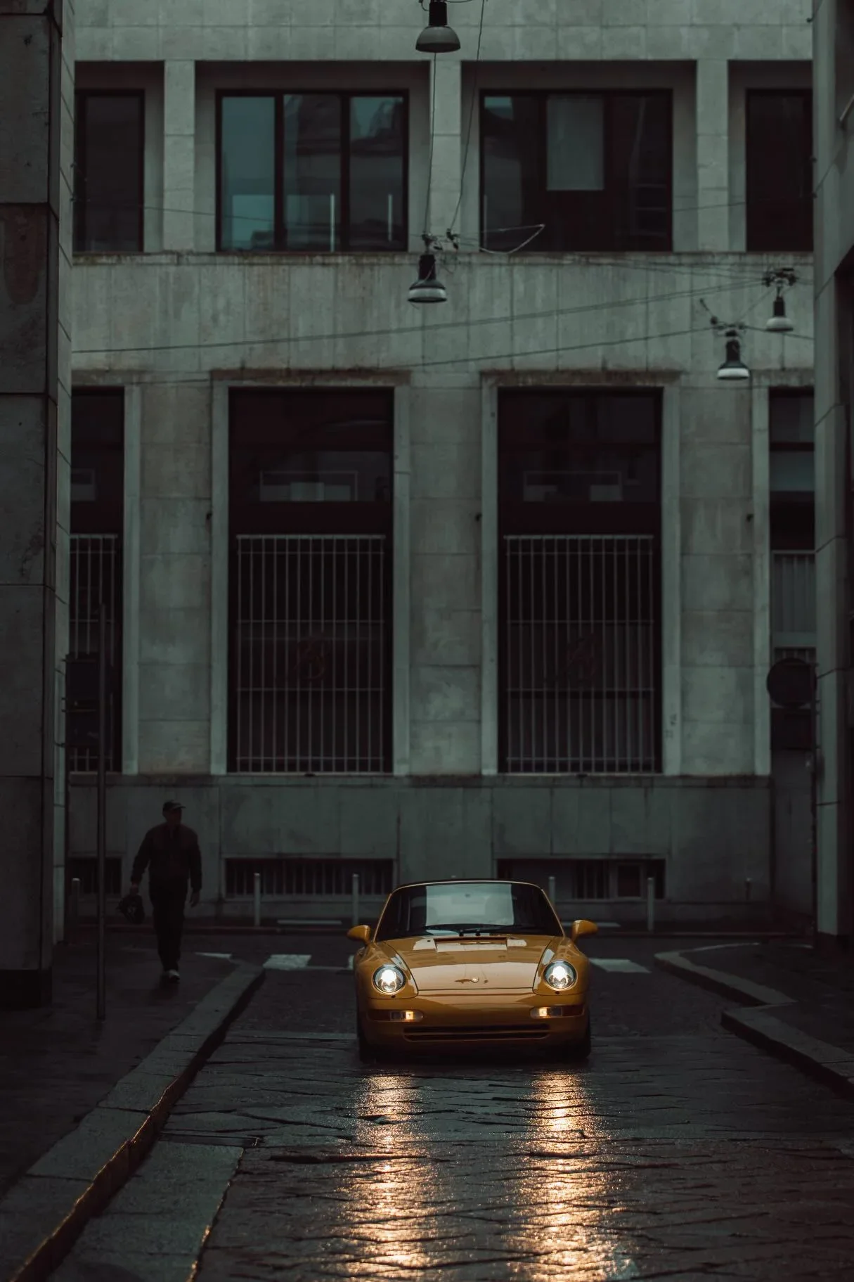 Daisy, a yellow Porsche 993 Carrera Cabrio in a rainy Milan street