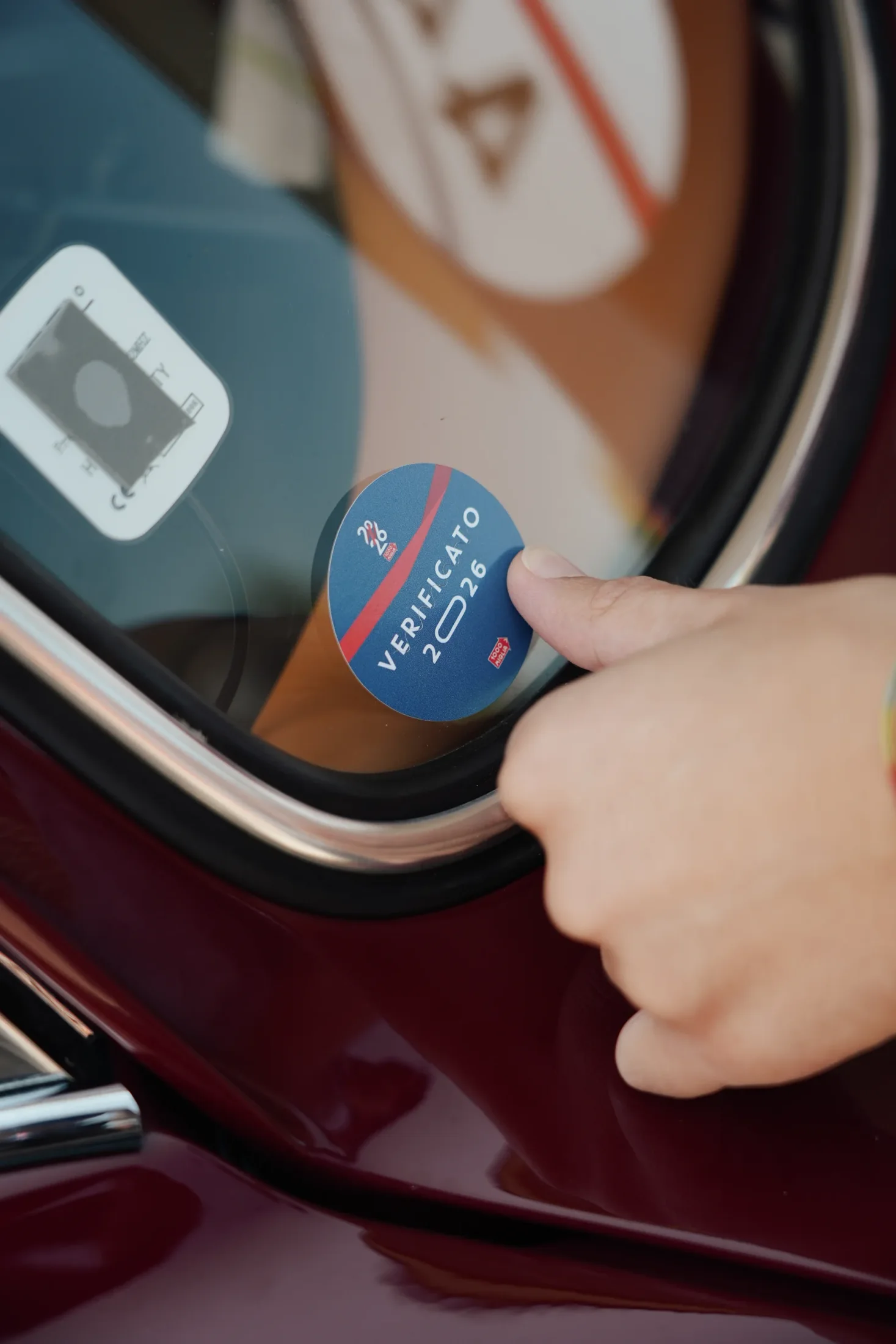 Applying the 1000 Miglia 2026 verification sticker to a burgundy Porsche